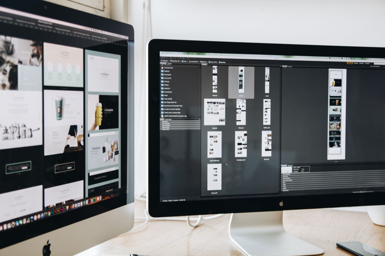A sleek modern desk setup with two computer monitors showing web design work, highlighting technology and productivity.